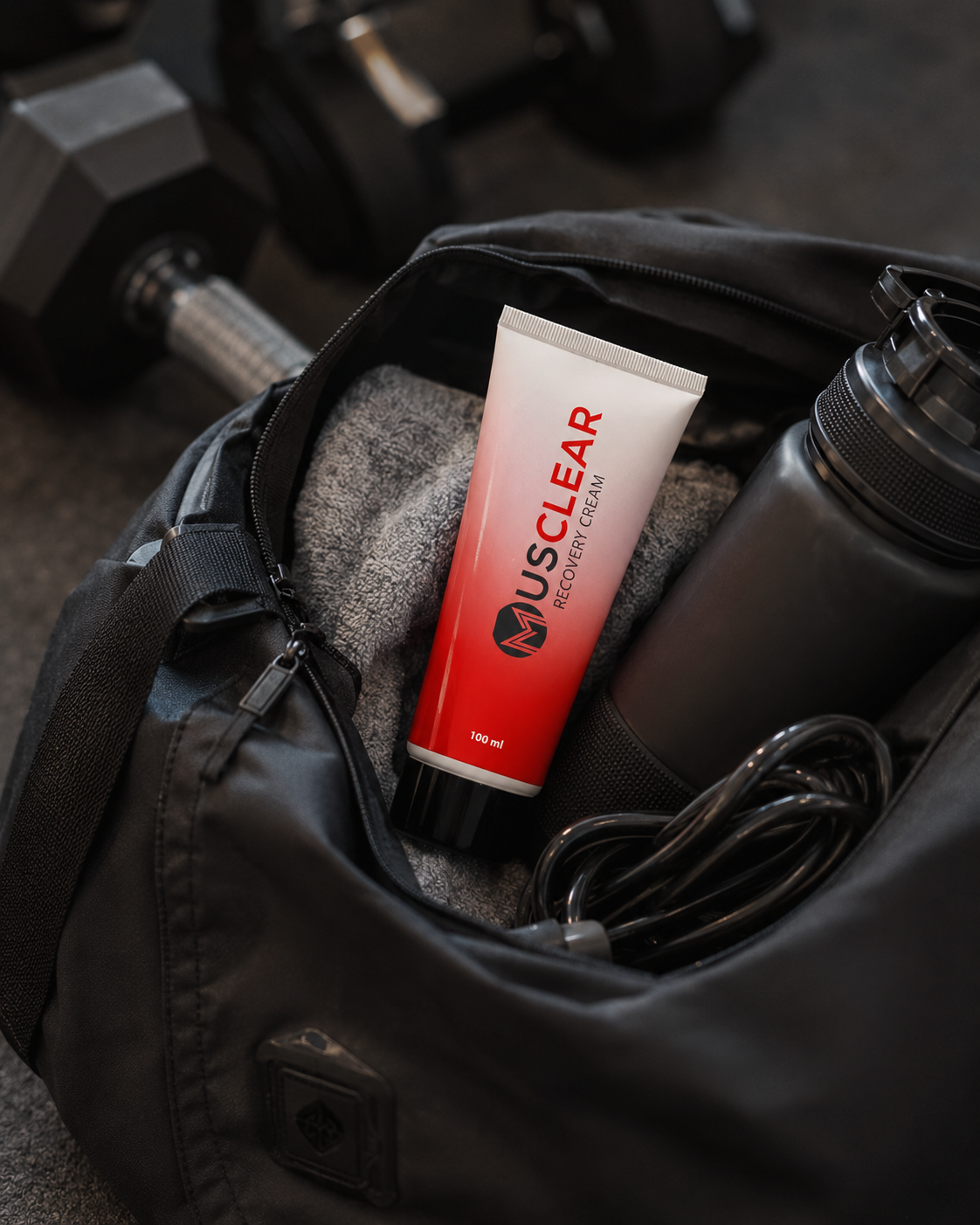 Musclear Recovery Cream in een sporttas met halters, bidon en springtouw