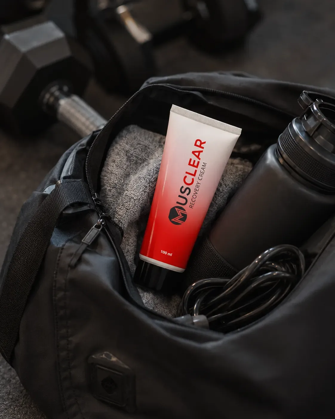 Musclear Recovery Cream in een sporttas met halters, bidon en springtouw
